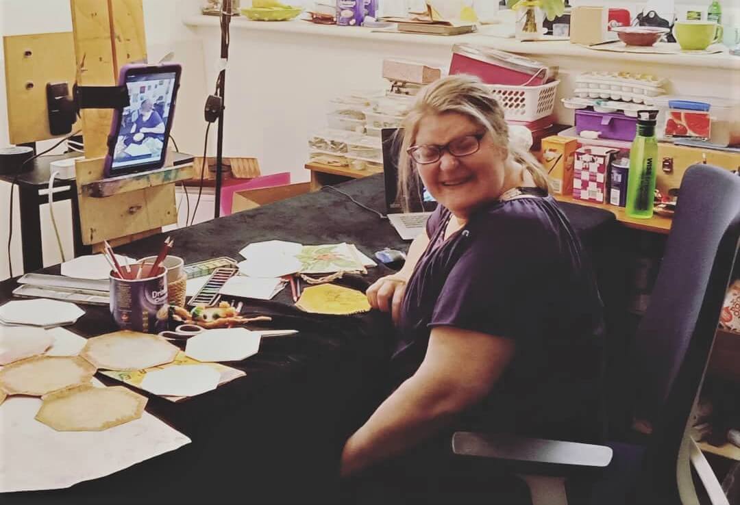 Deb sitting in her art studio smiling