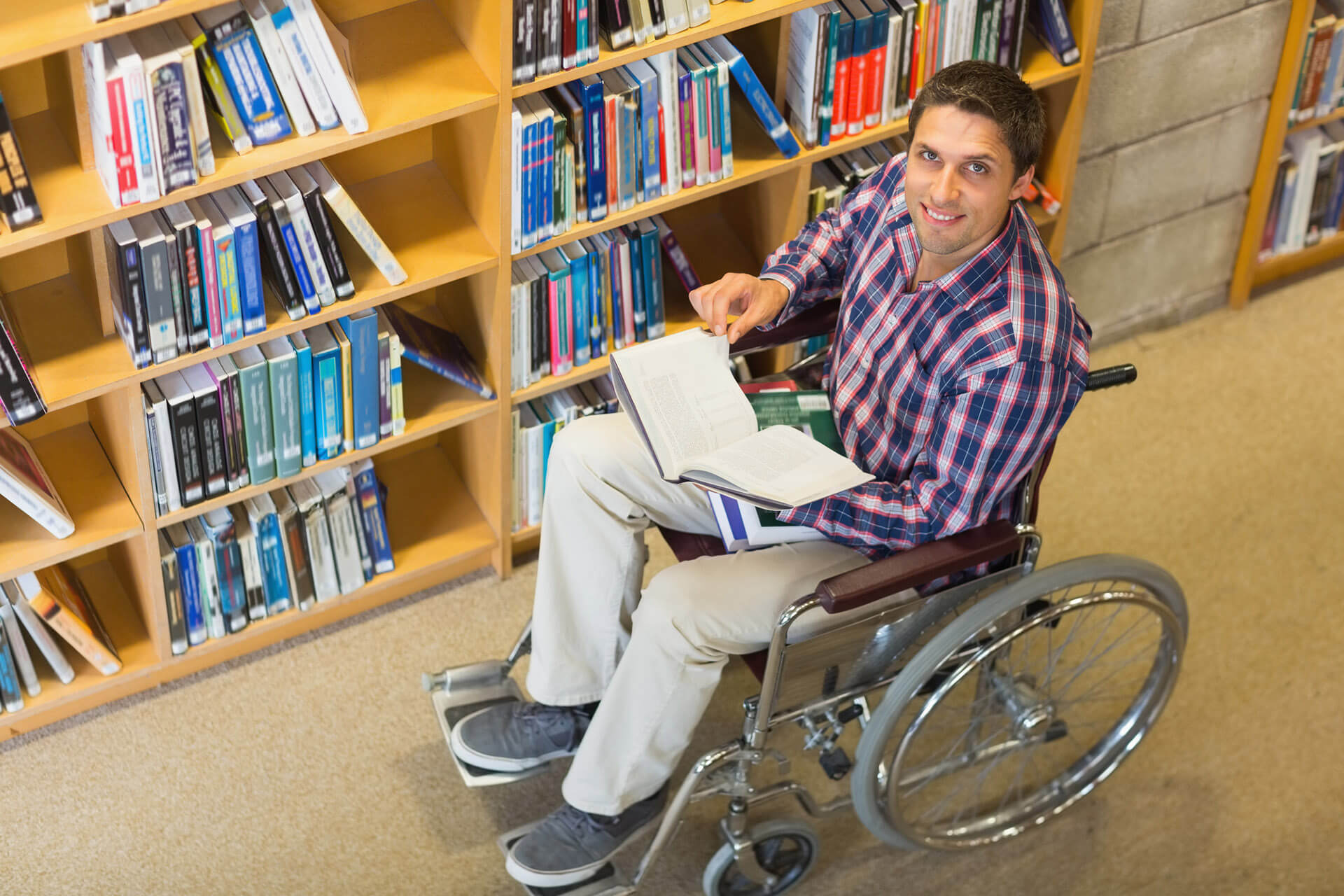 A man using a wheelchair browses books in a library