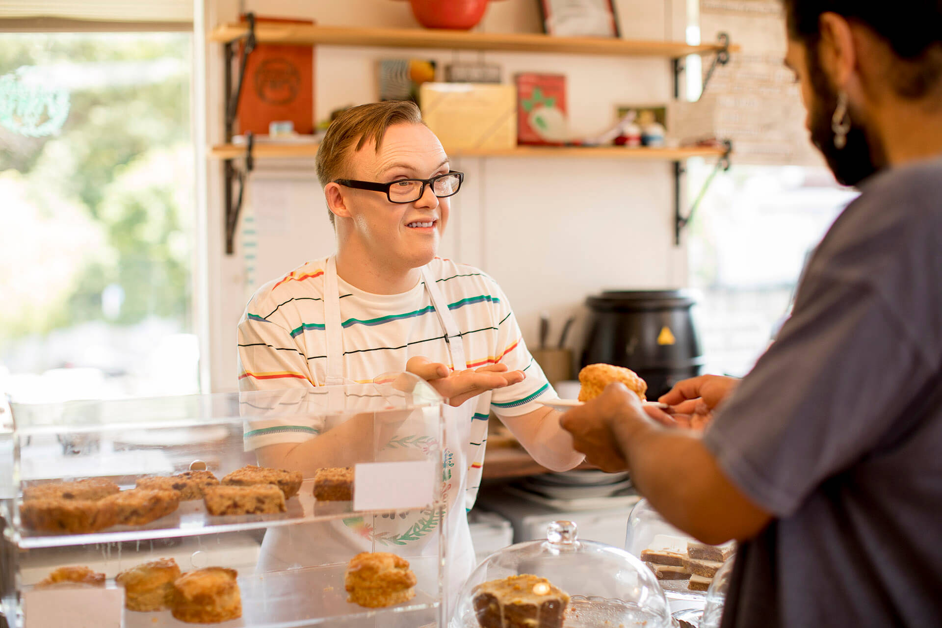 A staff member with disability serves a customer in a bakery
